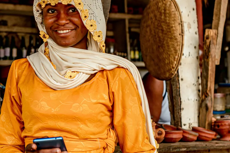 A market vendor smiling with her phone at her stall