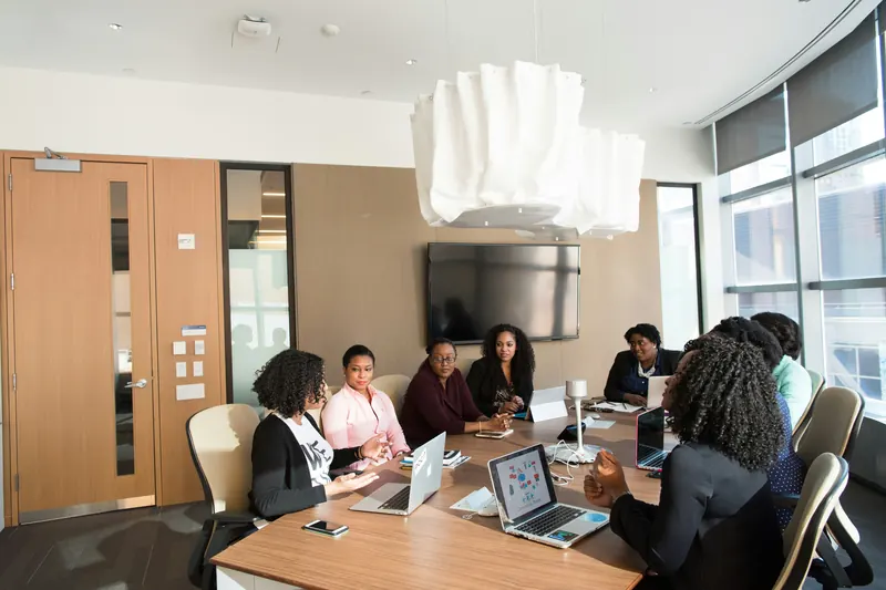 A team meets around a conference table with their laptops