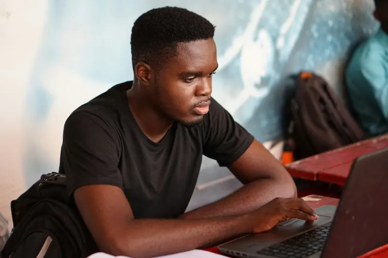 A young developer writing code on his laptop